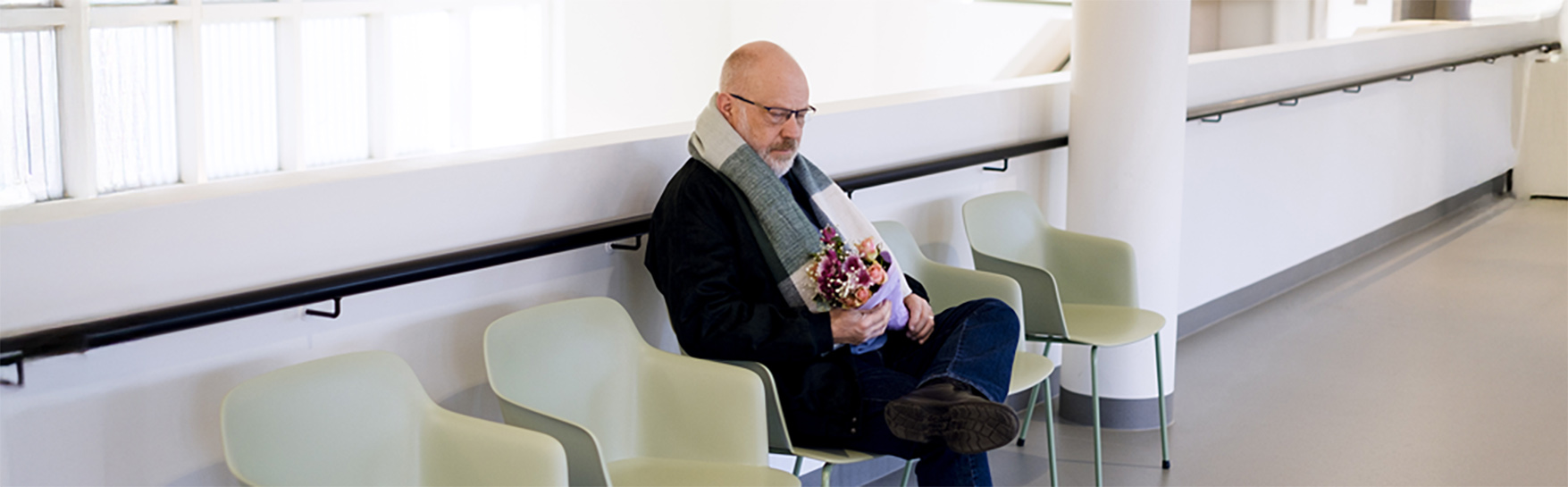 A man sits on a chair with a bouquet of flowers.